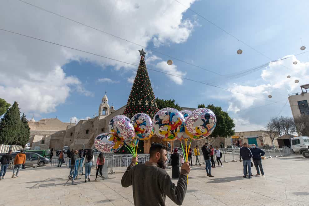 A Palestinian vendor sells balloons in Manger Square, adjacent to the Church of the Nativity in Bethlehem where events have been scaled down because of the pandemic (Nasser Nasser/AP)