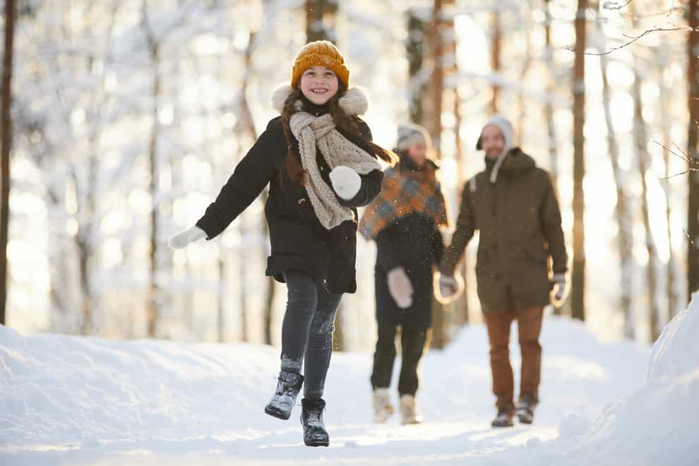 Full length portrait of happy little girl running towards camera in winter forest while enjoying walk with family (iStock/PA)