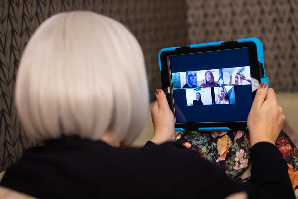 A woman takes part in a Zoom call on a tablet