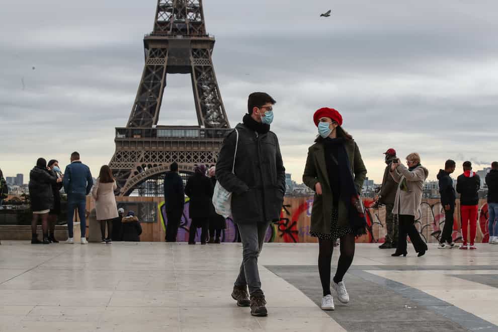 People wearing face masks walk near the Eiffel Tower in Paris