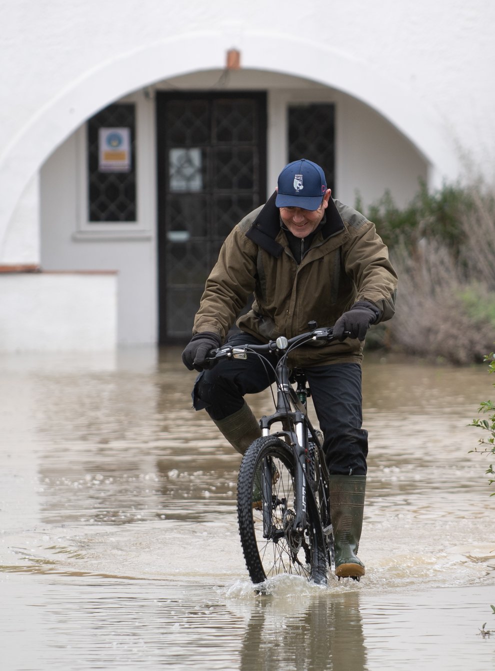 A man cycles through flood water at The Barn Hotel in Bedford, after residents living near the River Great Ouse in north Bedfordshire were “strongly urged” to seek alternative accommodation due to fears of flooding (Joe Giddens/PA)