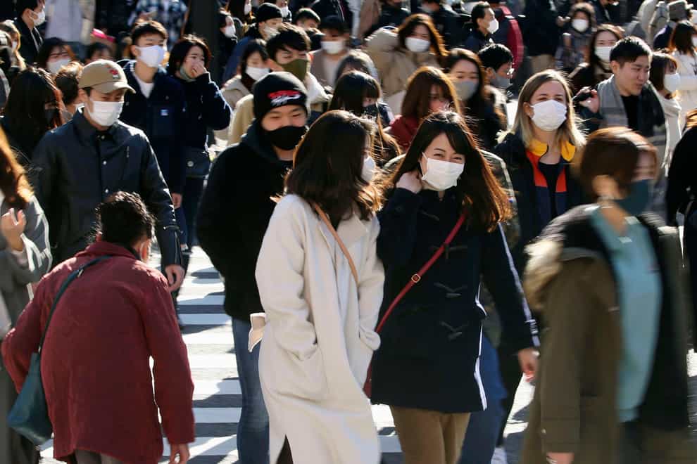 People wearing face masks to help curb the spread of the coronavirus walk around the scrambled intersection at the Shibuya shopping district in Tokyo