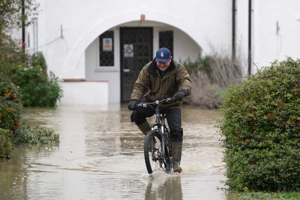 A man cycles through flood water at The Barn Hotel in Bedford