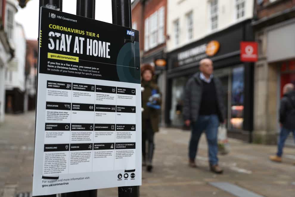 People walk past a Government coronavirus Tier 4 sign on the High Street in Winchester (Andrew Matthews/PA)