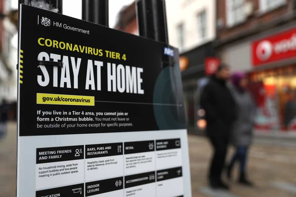 People make their way past a Government coronavirus Tier 4 sign on the High street in Winchester