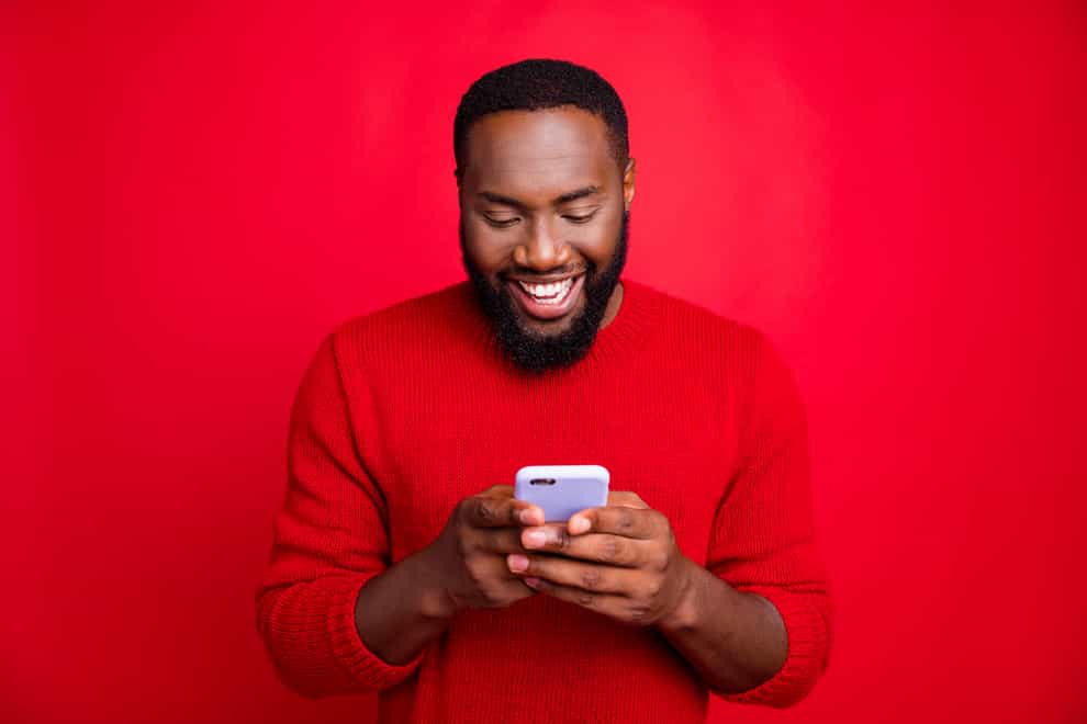 Happy smiling black man holding a new mobile phone