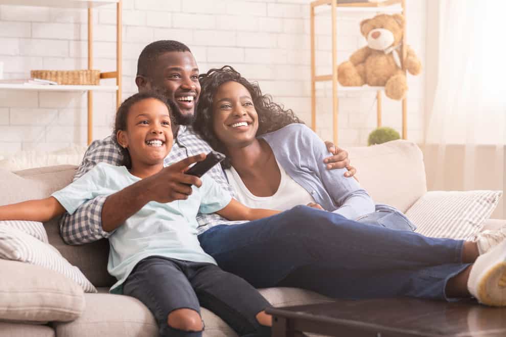Happy black family at home on the sofa watching TV