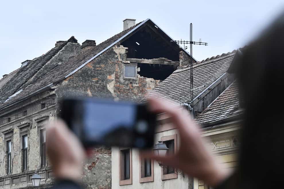 A resident takes a photograph of the damage caused by an earthquake in Sisak, Croatia