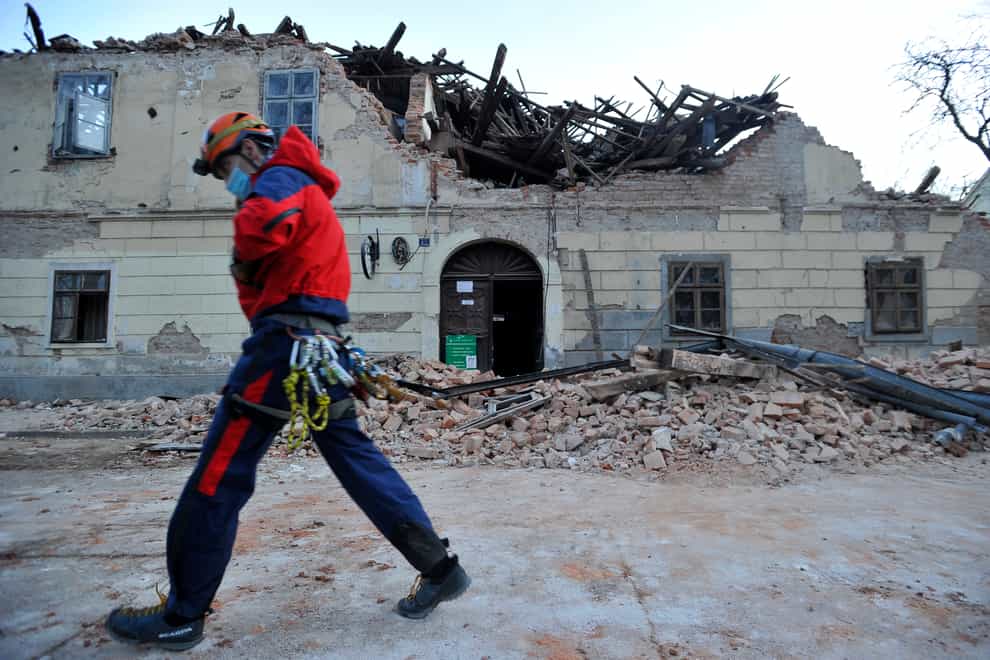 A rescuer walks past a building damaged in an earthquake in Petrinja, Croatia
