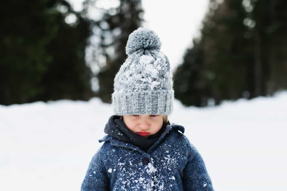 A young child looking grumpy in the snow