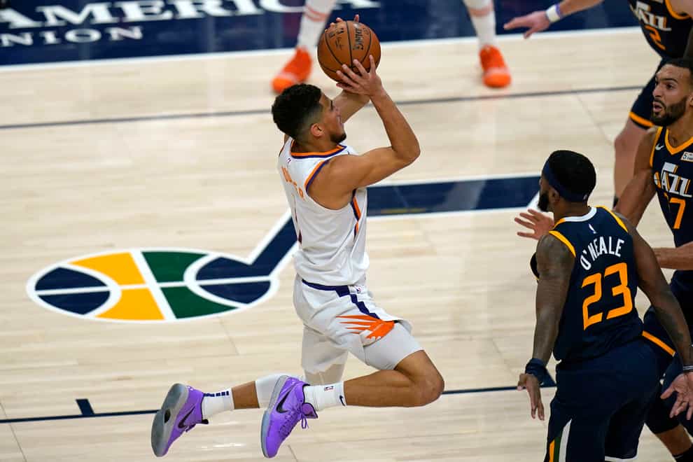Phoenix Suns guard Devin Booker shoots as Utah Jazz’s Royce O’Neale (23) and Rudy Gobert (27) watch during the second half of an NBA basketball game