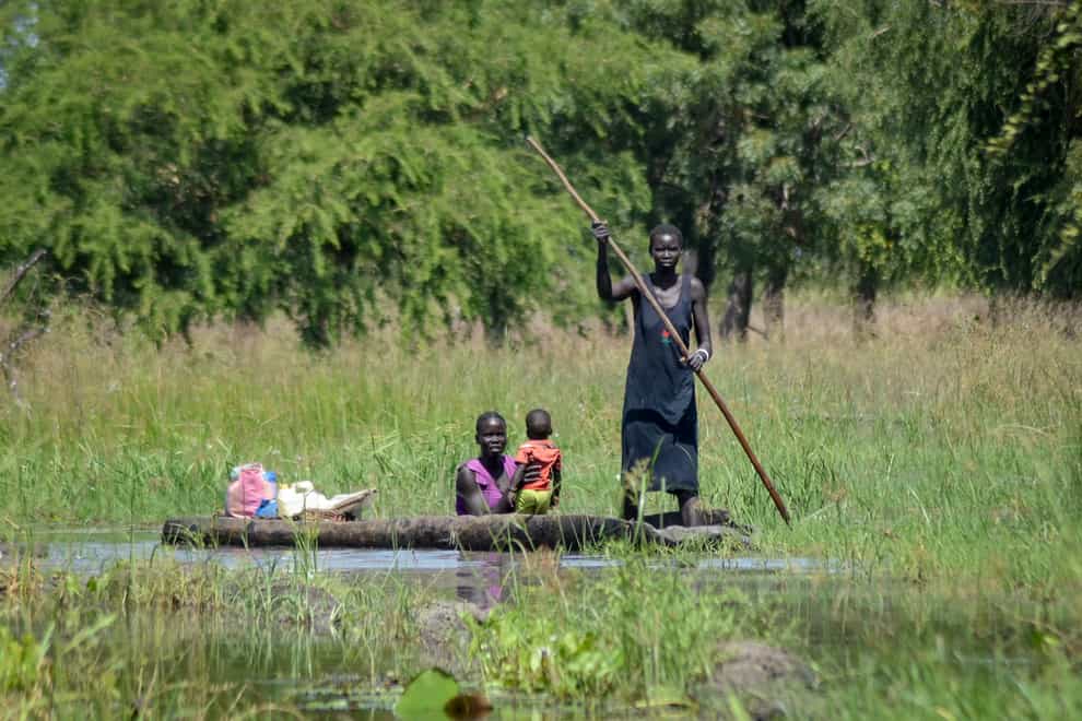 A mother holds her baby as she is transported by dugout canoe through floodwaters in the village of Wang Chot, Old Fangak county, Jonglei state, South Sudan