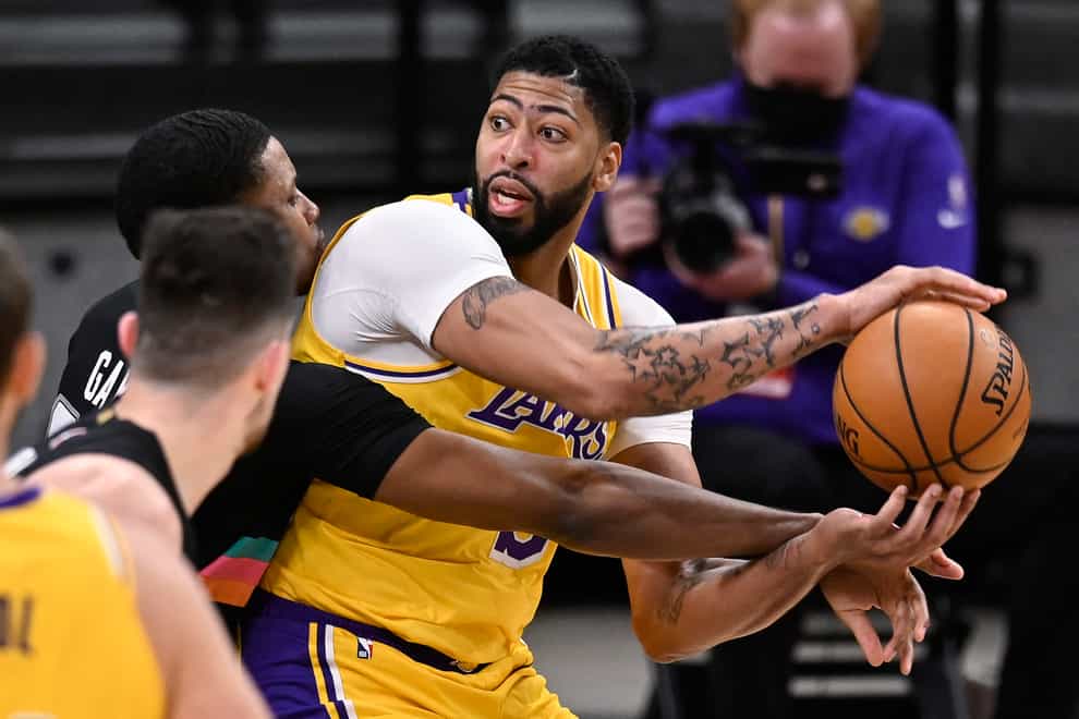 Los Angeles Lakers’ Anthony Davis, right, keeps the ball from San Antonio Spurs’ Rudy Gay, left rear, and Drew Eubanks during the first half of an NBA basketball game