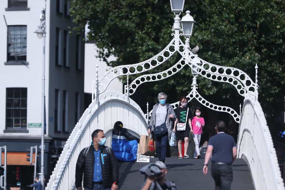 People wearing masks crossing the Ha’penny Bridge in Dublin city centre (Niall Carson/PA)