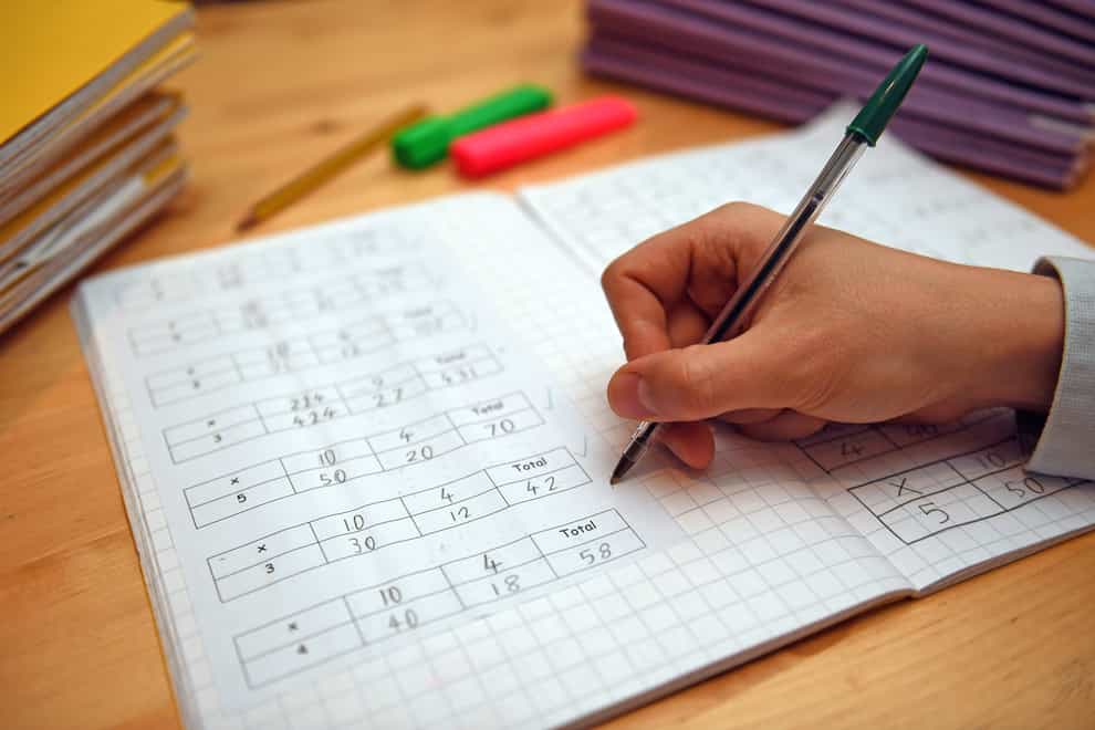 A primary school teacher marking a pupil’s maths homework