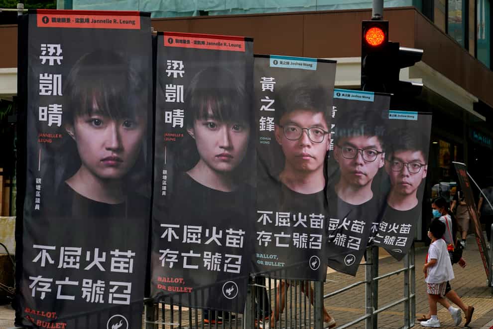 Banners of pro-democracy candidate Joshua Wong, wearing glasses, are displayed outside a subway station in Hong Kong