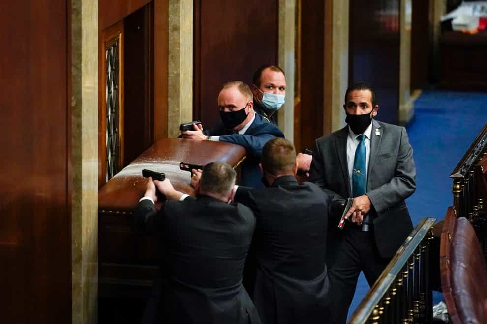 US Capitol Police with guns drawn stand near a barricaded door as protesters try to break into the House Chamber at the US Capitol