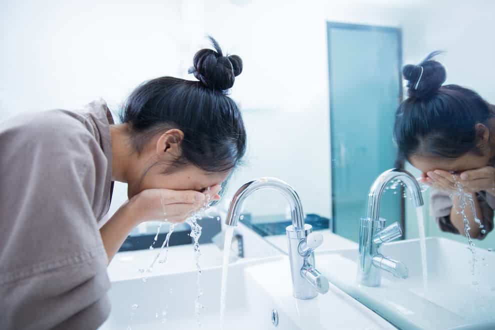 Woman washing face with water
