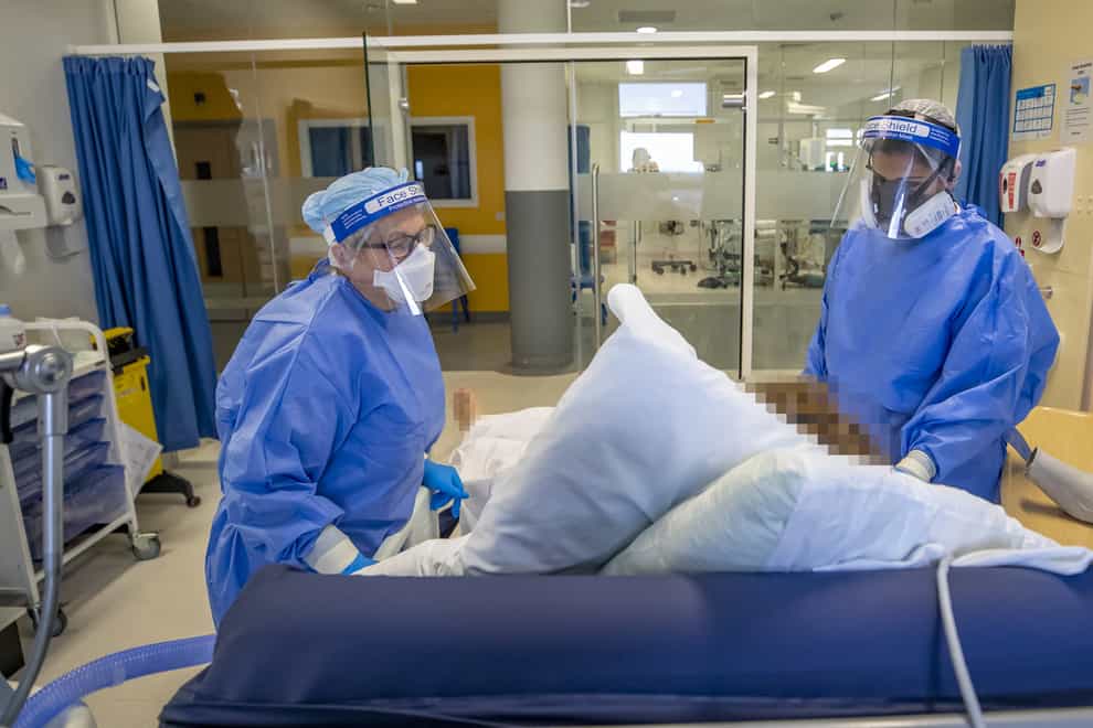 Health workers wearing full personal protective equipment tend to a patient on the intensive care unit at Whiston Hospital in Merseyside