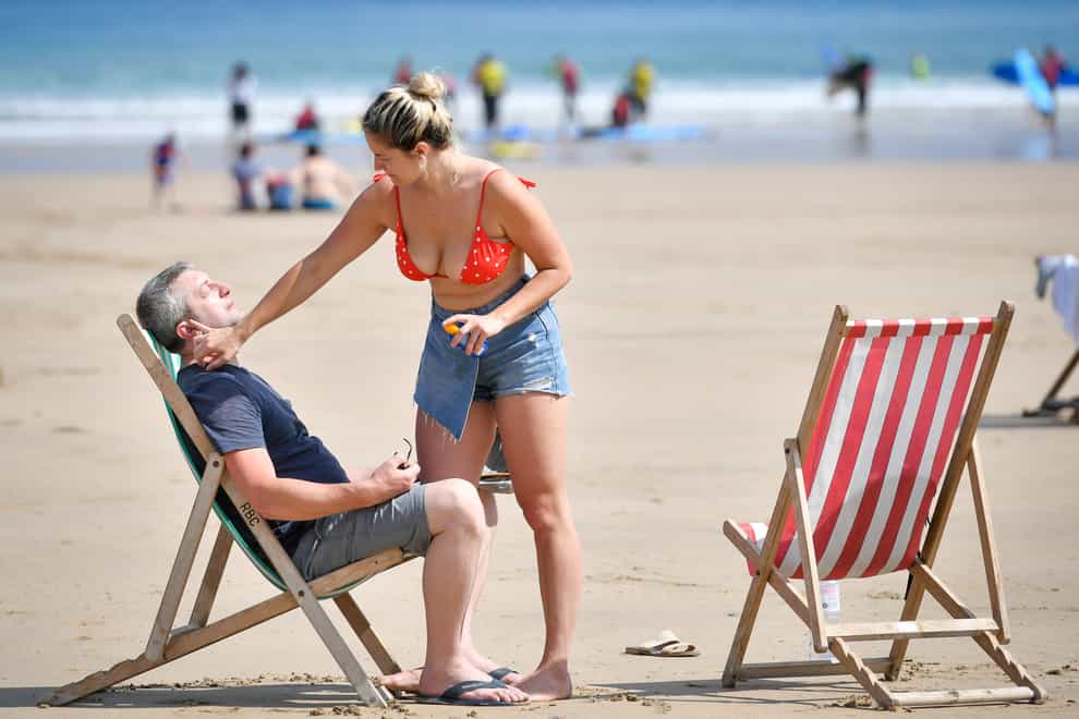 People apply sunscreen on the beach in Newquay, Cornwall