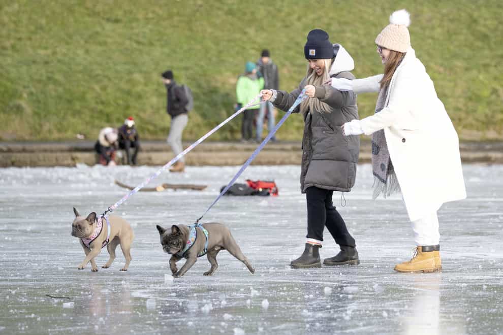 People walk their dogs across the frozen pond in Inverleith Park, Edinburgh