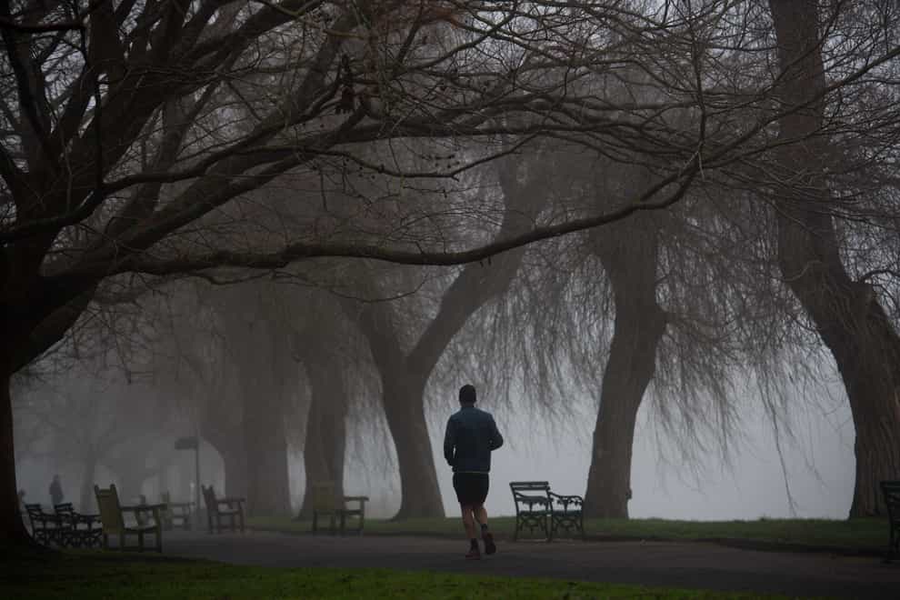 A runner exercises in a cold and foggy St Nicholas’ Park in Warwick