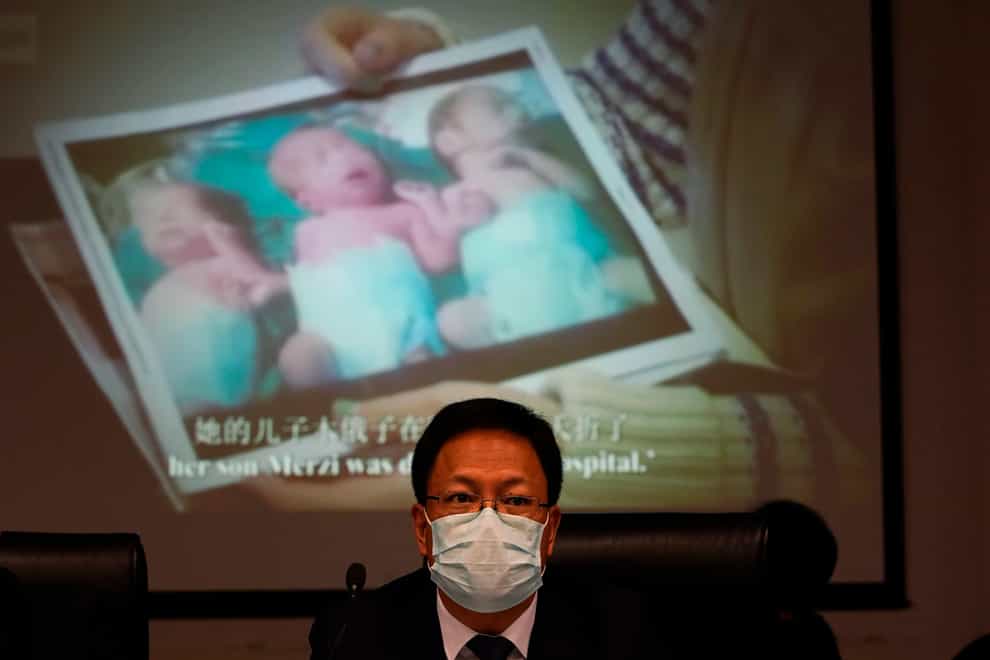 Xu Guixiang, a deputy spokesperson for the Xinjiang regional government, looks up near a slide showing a photo of Uighur infants during a press conference (Ng Han Guan/AP)