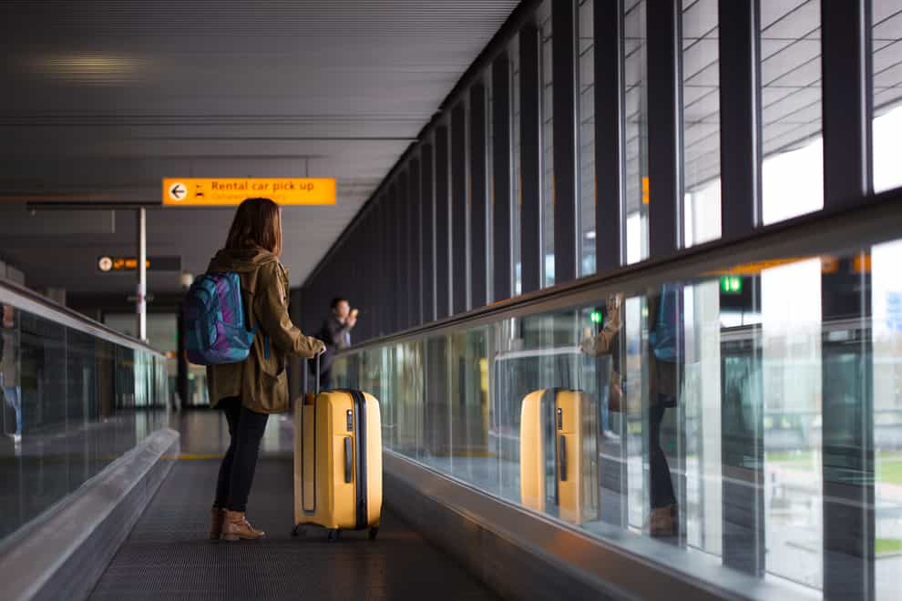 woman with suitcase and backpack on airport travelator