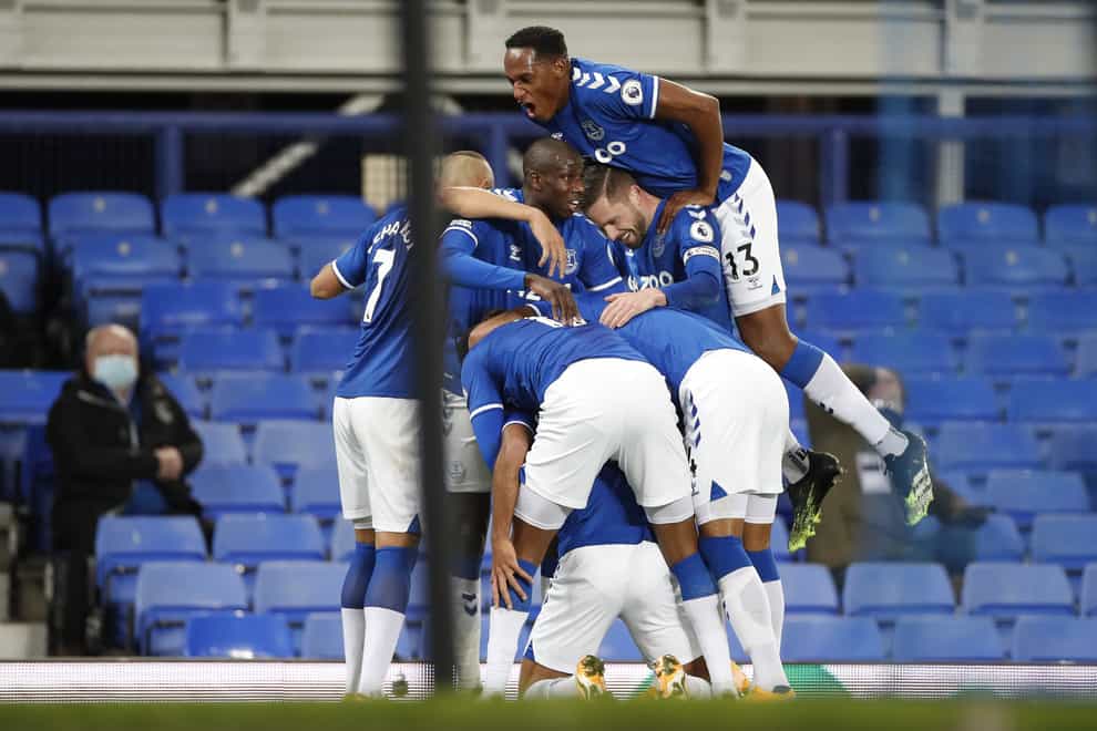 Everton players celebrate in a mass huddle after scoring a goal