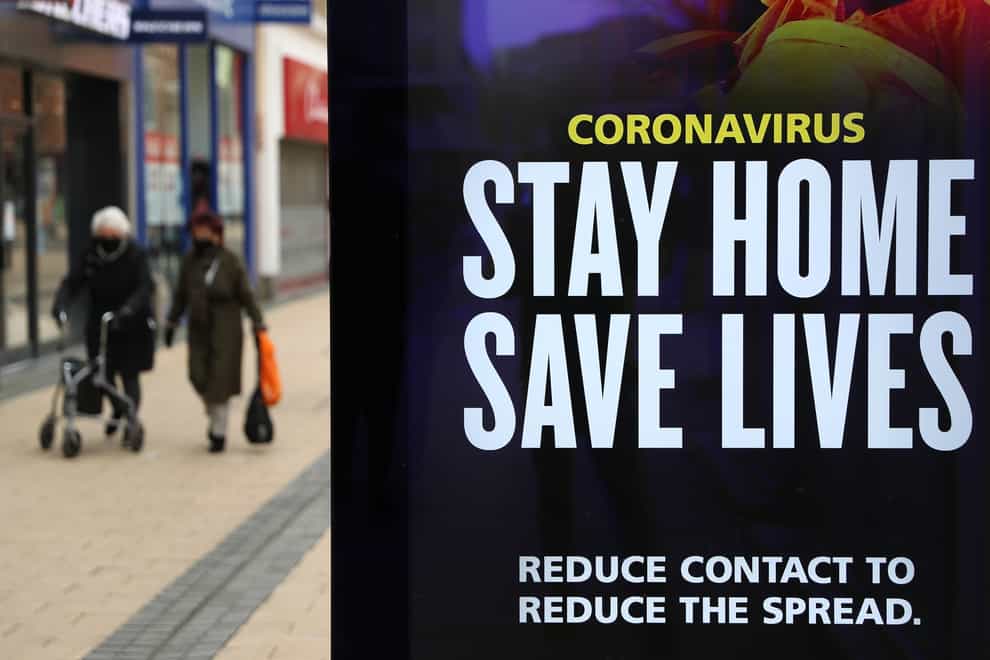People walk past a ‘Stay Home Save Lives’ sign in Bristol