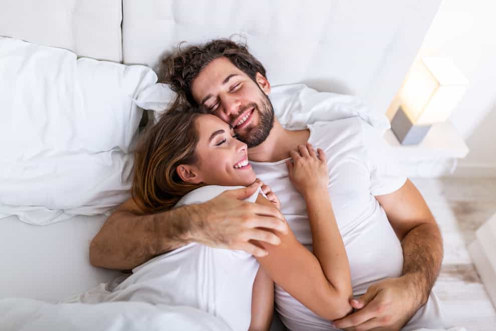 White man and woman lying in bed together, looking intimate and happy