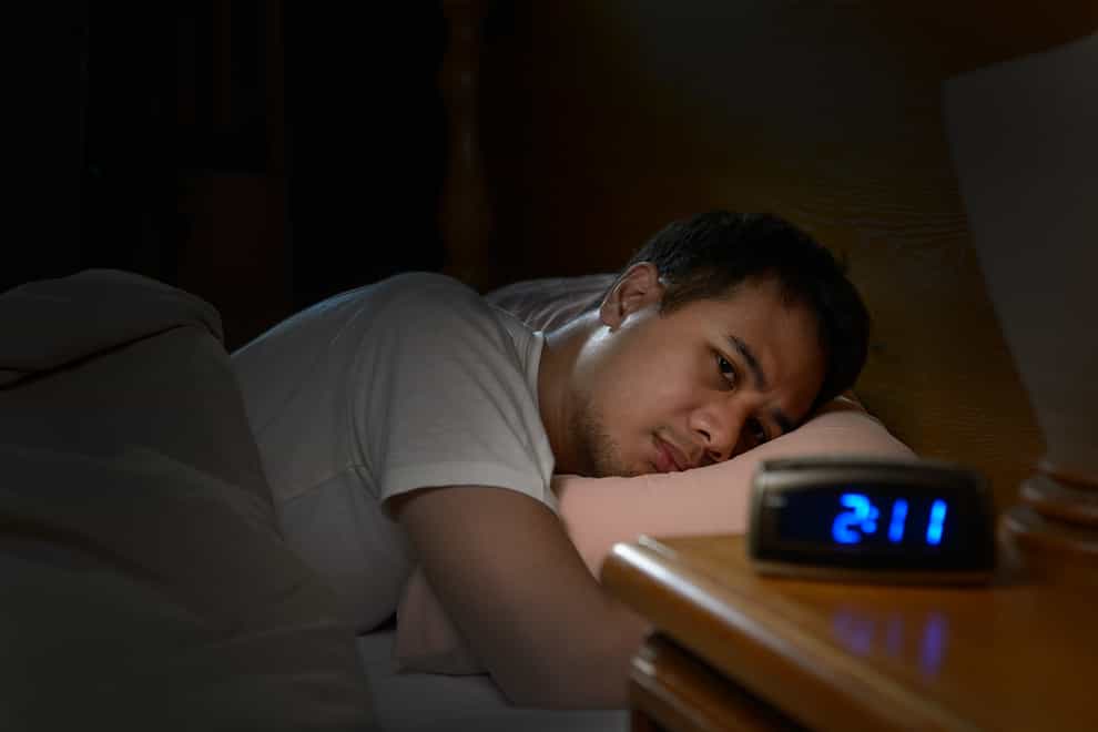 Insomniac man looking at alarm clock