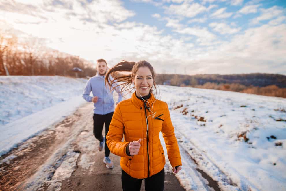A white woman and man running outdoors on a snowy track