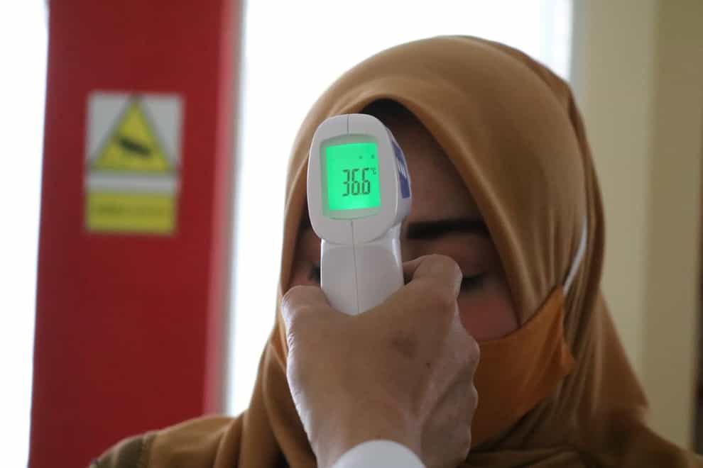 A woman has her temperature read via a temperature scan of her forehead
