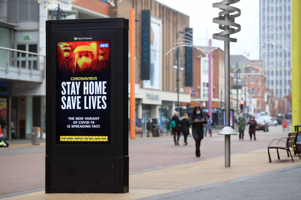 People pass a Stay Home, Save Lives electronic board in Leicester