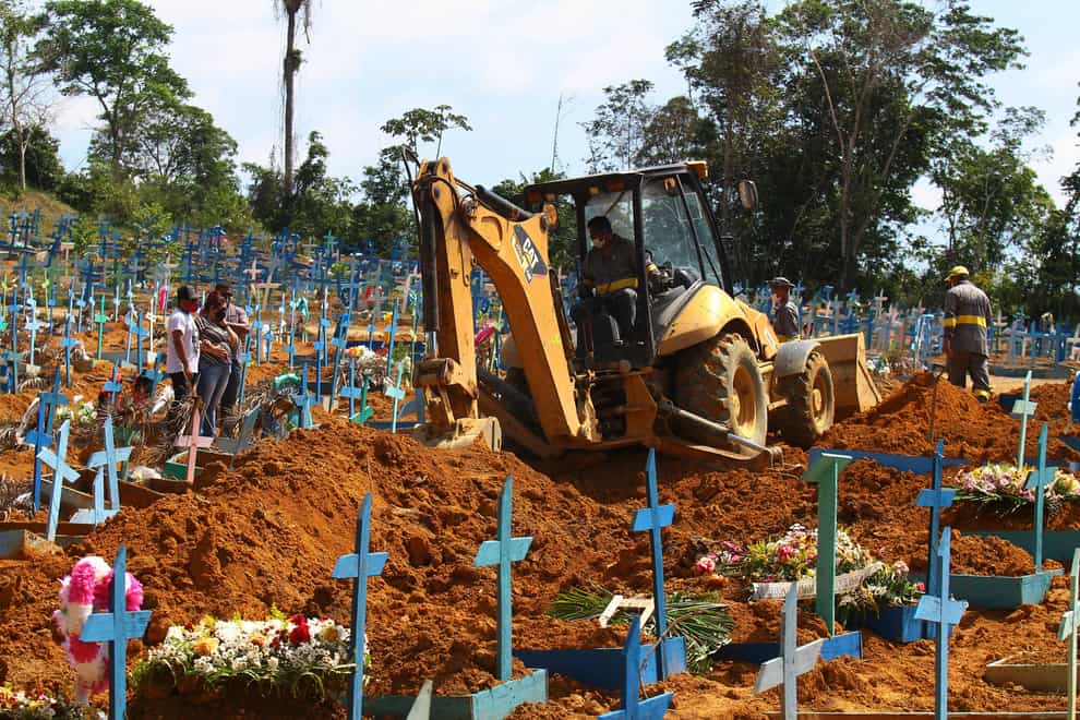 A bulldozer moves earth over a coffin in Manaus, Brazil (Edmar Barros/AP)