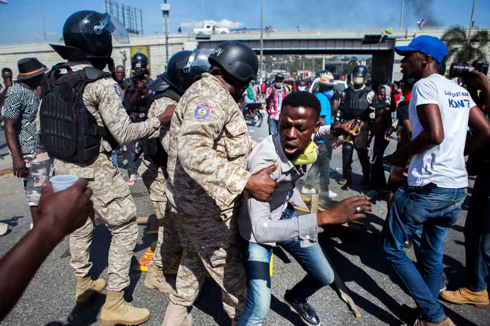 Police officers prevent a protester from fueling a burning barricade during a demonstration demanding the resignation of President Jovenel Moise, in Port-au- Prince, Haiti