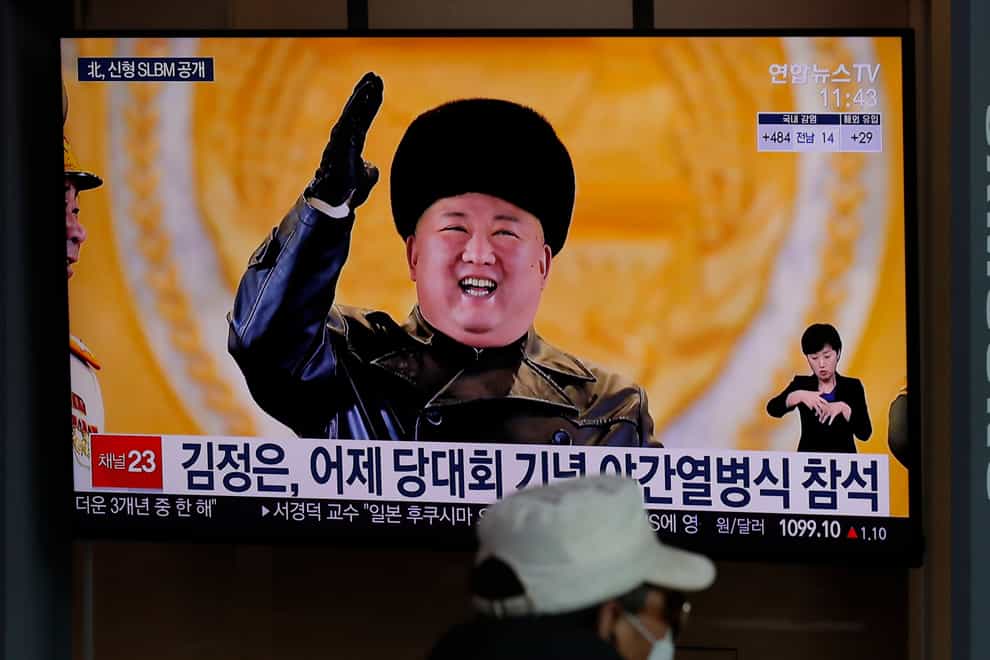 A man wearing a face mask sits in front of a TV screen showing North Korean leader Kim Jong Un (Lee Jin-man/AP)