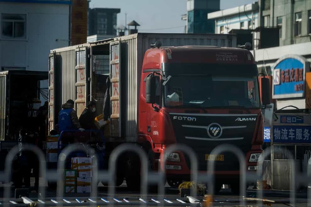 Workers wearing face masks to help curb the spread of coronavirus load frozen foods to a lorry in Beijing (Andy Wong/PA)