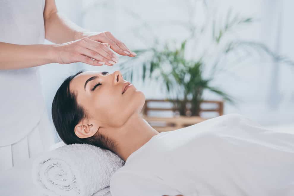 woman with closed eyes receiving reiki treatment above head
