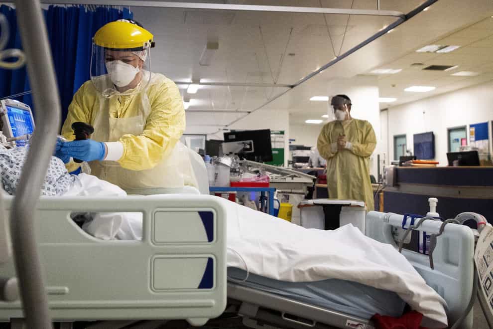 A nurse works on a patient in an ICU