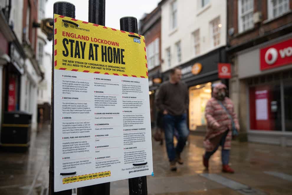People walk past a Government sign warning people to stay at home on the High Street in Winchester