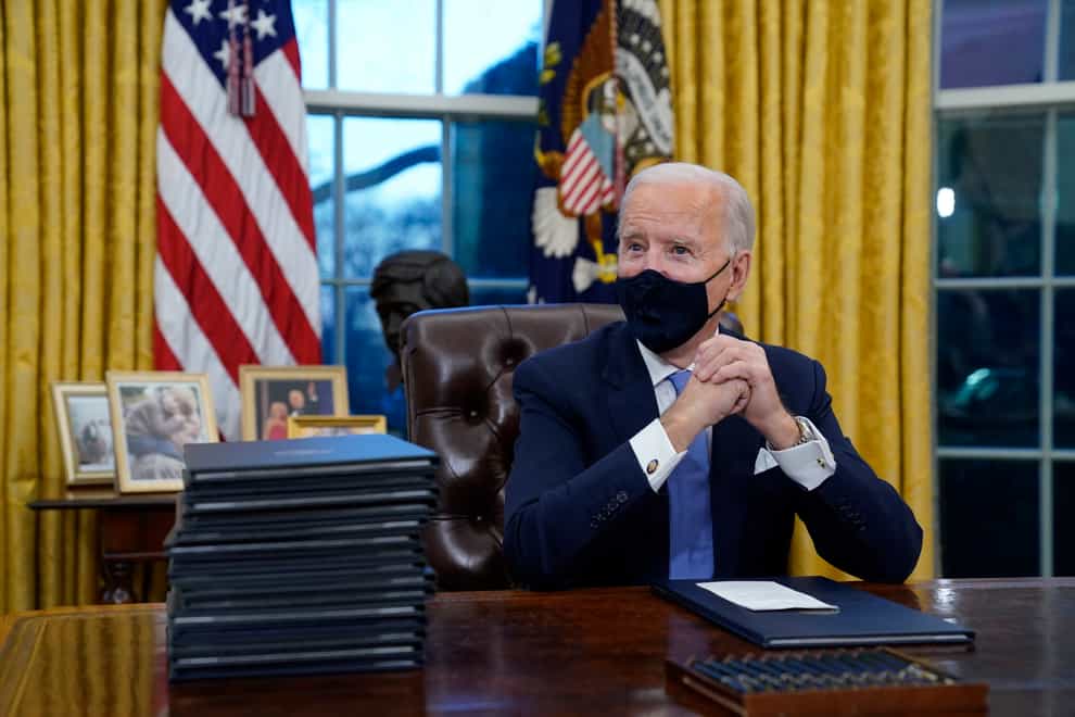 President Joe Biden waits to sign his first executive order in the Oval Office of the White House