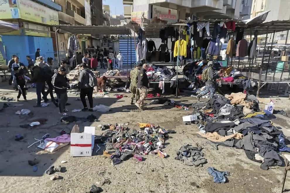 People and security forces gather at the site of a deadly bomb attack in a market selling used clothes in Iraq
