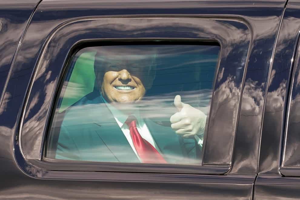 President Donald Trump gestures to supporters from inside a vehicle