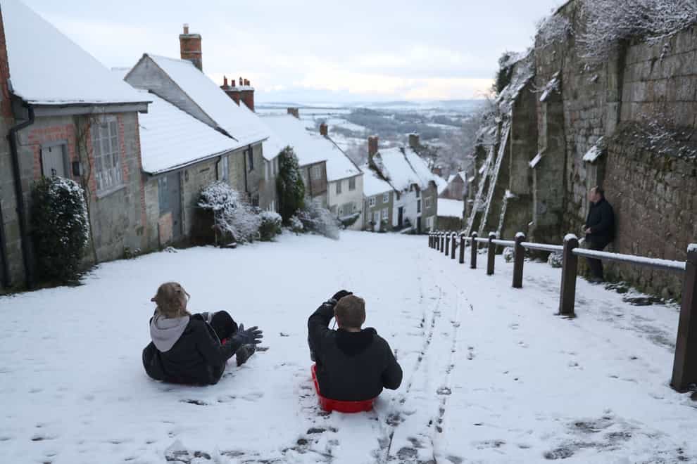 Children sledge down Gold Hill in Shaftesbury, Dorset