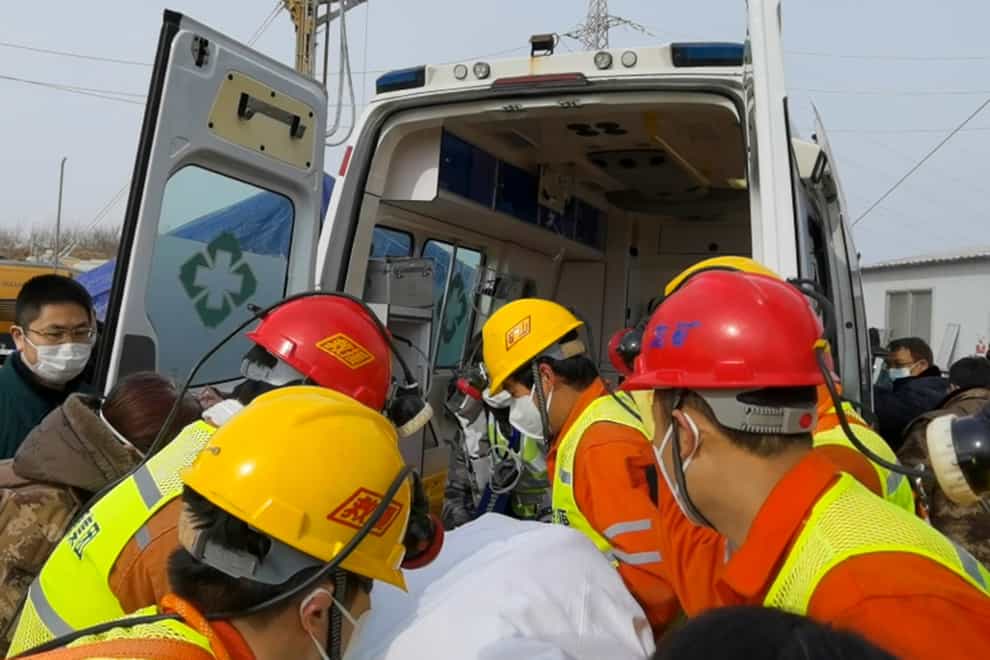 Rescuers carry a miner who was trapped in a gold mine