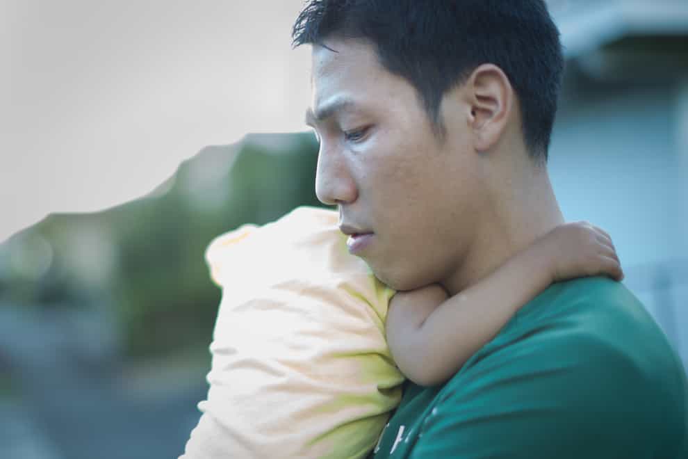 Tired man holding a baby