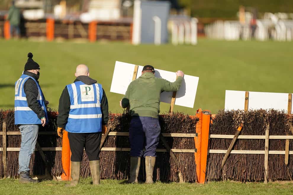 Racecourse staff place signs as hurdles are bypassed at Plumpton