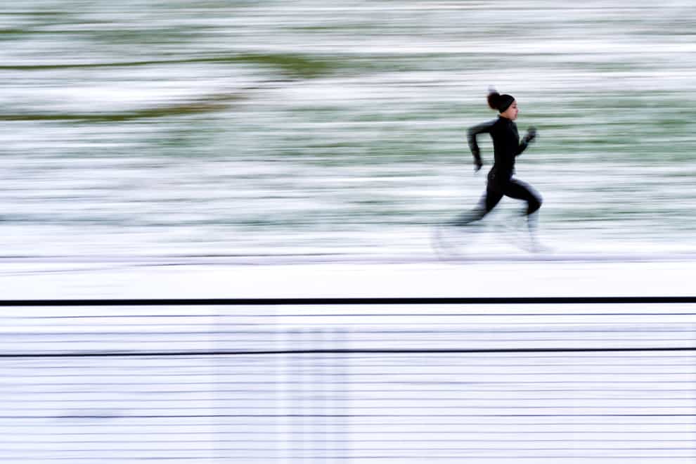 A runner in the snow on a running track in Isleworth, London